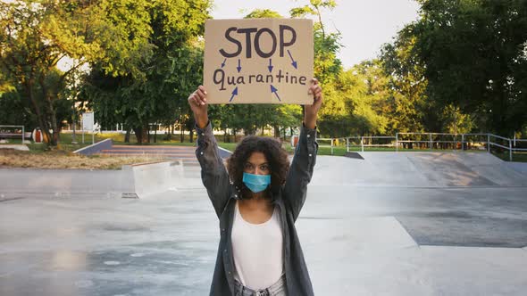 Darkskinned Lady in Blue Protective Mask and Casual Outfit is Raising Up Cardboard Tablet with alt