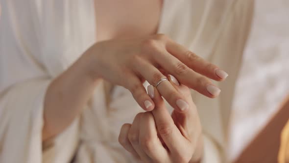 Bride in night gown, veil wearing engagement ring near window, Close-up, Wedding morning alt