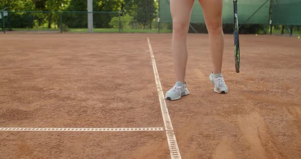Low Angle Faceless Sportswoman Warming Up Before Tennis Match Hitting the Ball on Clay Court alt