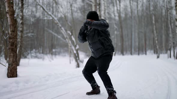 Professional MMA Fighter Punches on the Background of Nature in Winter in Snowy Weather alt