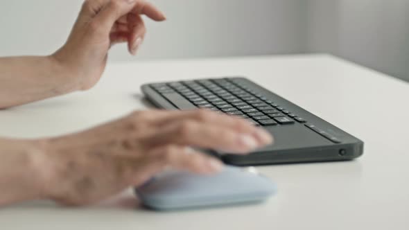 Female Hands Typing on Keyboard and Holding Computer Mouse on Light Background