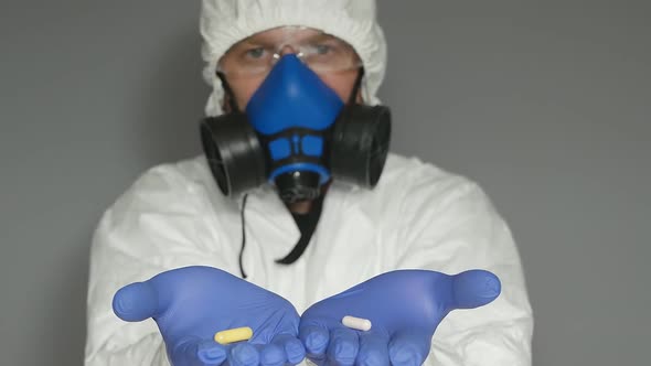 A Male Virologist in a Protective Suit Wearing a Mask and Goggles Holds Out Two Hands and Opening