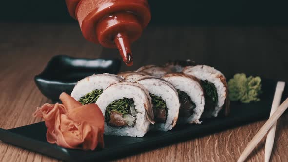 Appetizing Sushi is Poured with Sweet Sauce on a Wooden Table in Restaurant alt
