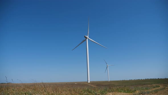 Working Twisting Windmills Stand in a Field in Summer alt