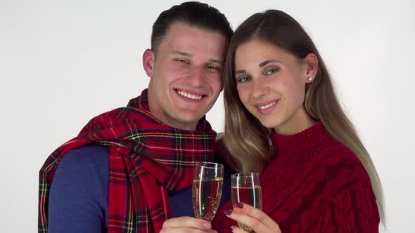 Young Couple Smiling, Toasting with Their Champagne Glasses To the Camera alt