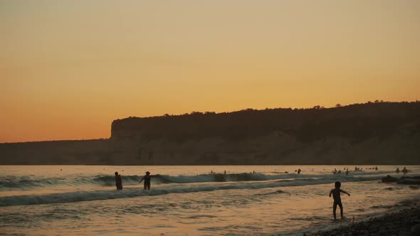 Silhouettes of People Swimming at Sunset