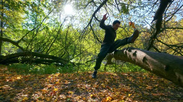 An Man Doing A Jump Exhibition Over A Tree Trunk During Autumn Season In Lithuania- Tracking Shot alt