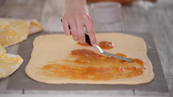 Closeup of a Woman Preparing Roll Buns with Apricot Jam