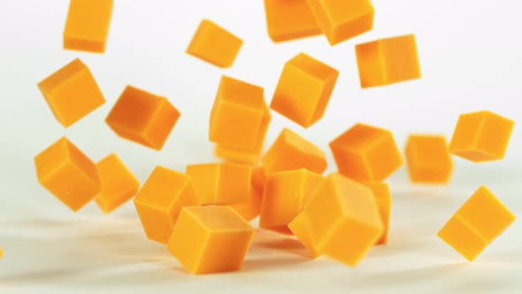 Super Slow Motion Shot of Cheddar Cheese Cubes Falling on White Background at 1000 Fps. alt