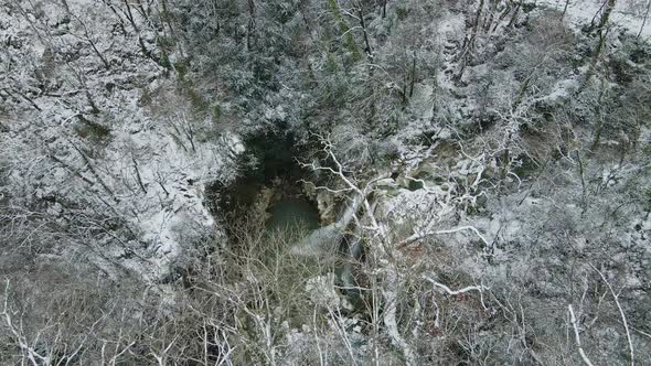 Waterfall Flowing From White Rocks Into a Lake in the Forest alt
