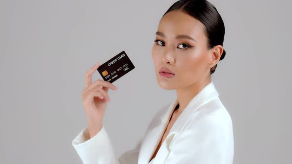 Beautiful Asian businesswoman showing credit card and looking at camera alt