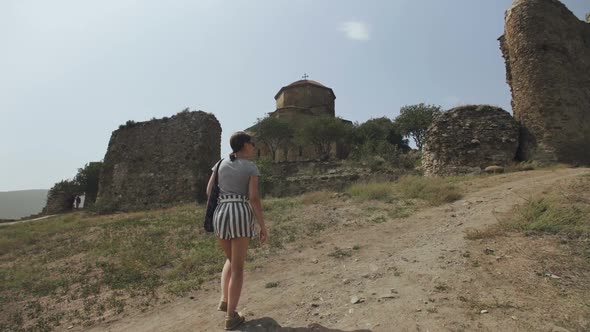 Girl Climbs Up the Hill To Old Stone Church on the Top of the Mountain. Jvari Monastery, Georgia alt