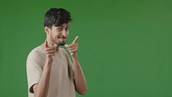 Positive Smiling Arab Young Man Guy Stand in Green Studio Showing Hey you Gesture Pretending alt