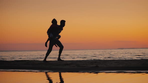 Brother Plays with Younger Sister on the Beach  Rolls Her on His Shoulders alt