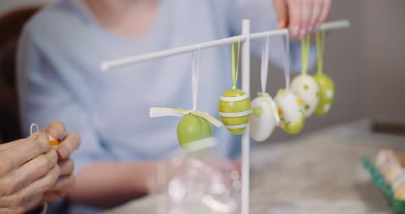 Senior Man and Granddaughter Decorating Table With Easter Eggs and Easter Decorations. alt