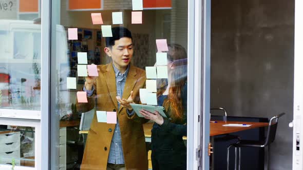 Business executives discussing over sticky notes alt