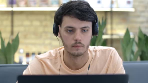 Closeup Portrait of Absorbed Handsome Caucasian Young Man in Headphones Surfing Internet on Laptop alt