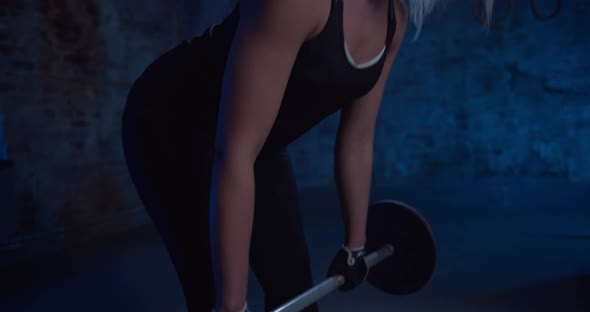 Fit Pretty Woman Performing the Deadlift Workout with Barbell in Gym