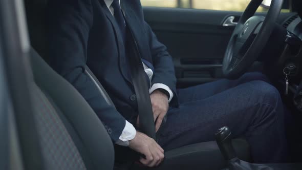 Unrecognizable Male Driver Fastening Seat Belt Sitting in Car alt