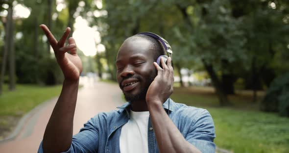 Afro-american Male in Headphones Singing in Park