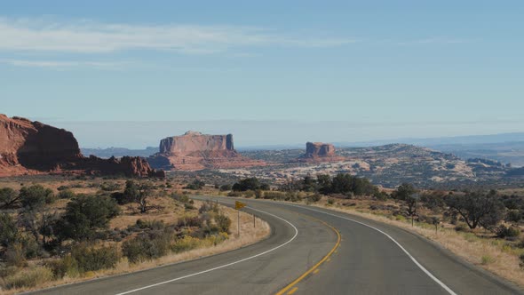 Driving On Empty Road In Amazing Arches Park In Utah With Red Rock Formations alt