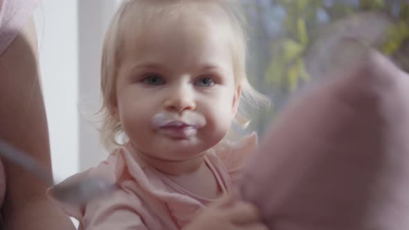 Close-up Face of Caucasian Little Girl Eating Baby Food alt
