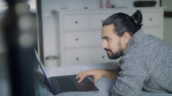 A Man in a Cozy Gray Knitted Sweater is Stuck on Social Media alt