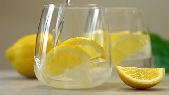 Soda Water is Poured Into Glass with Fresh Lemon Slices and Ice