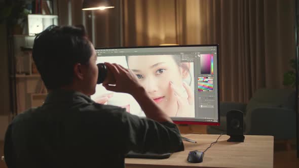 Male Digital Editor Drinking Coffee While Works In Photo Editing Software On His Personal Computer alt