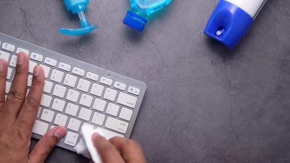 Man Hand Cleaning Keyboard with Disinfectant Wet Wipe alt