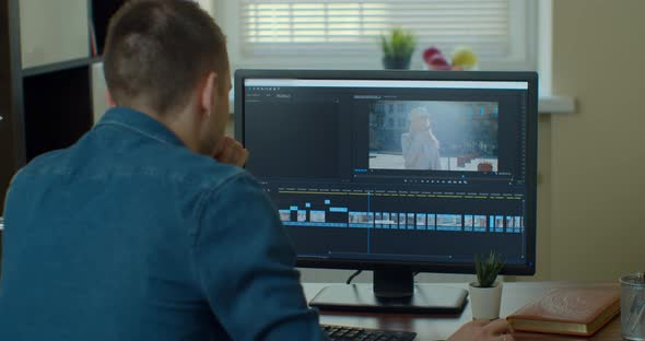 Male Video Editor Works with Footage and Sound on His Personal Computer. His Office Is Modern and alt