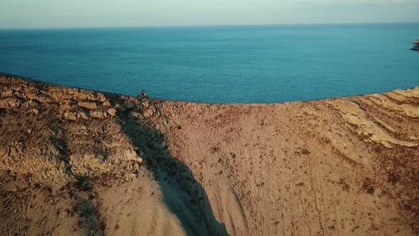 Drone View of Man on Motorbike Extremely Rides Across the Hills with Black Sea on Background in