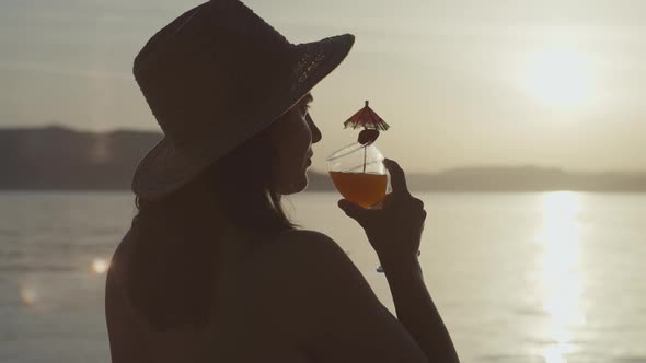 Slow Motion Video of a Girl Drinking a Cocktail at Sunset By the Sea alt