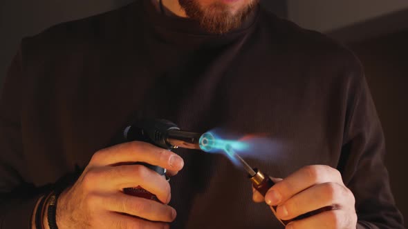 Man Heats Tool with Portable Torch