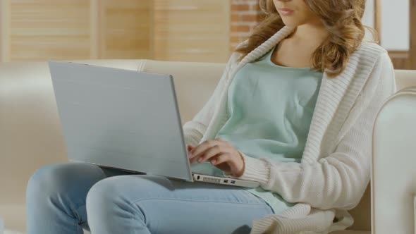 Female Freelancer Sitting on Sofa and Working on Laptop, Responding to E-Mail alt