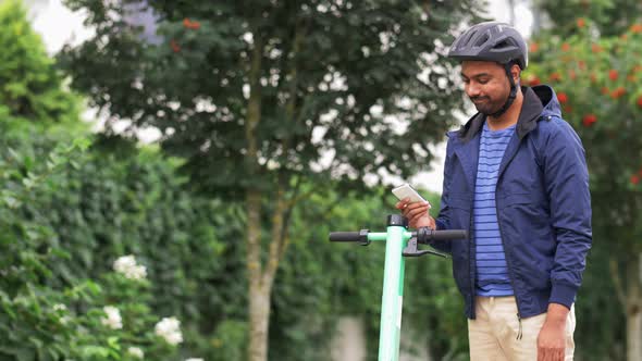 Man with Smartphone Riding Electric Scooter alt