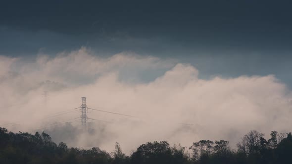 Aerial view high voltage power transmission towers or electricity pylon in fog on mountain.