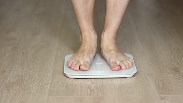 Man walking on scales measure weight. male wal checking BMI weight loss. human barefoot measuring 