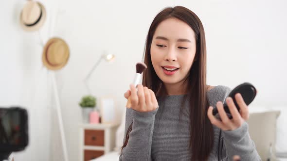 Young beautiful Asian woman professional beauty vlogger influencer recording make up tutorial video