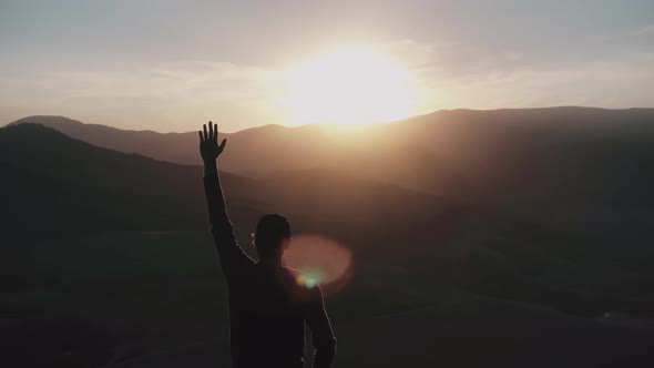 A Young Man Stands in the Rays of the Sunset and Pulls His Hand Up Aerial Survey of a Drone Which alt