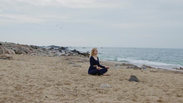 Young Woman Is Meditating On Beach