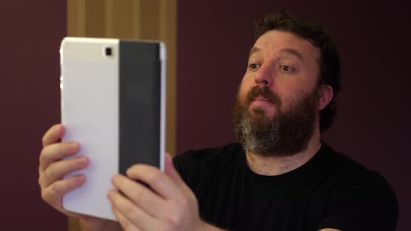Portrait of bearded man while looking for something on the tablet