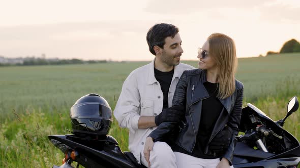 Beautiful Couple Stands Next to Sport Motorcycle on the Road Near Field