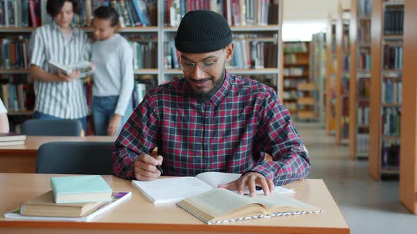 African American Student Learning in Library Reading Writing Sitting at Desk alt