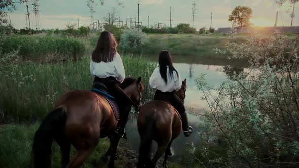 Brunette Girl Friends Ride Horses Wading River at Sunset
