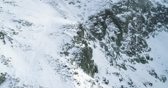 Backward Discover Aerial Over Winter Snowy Mountain with Mountaineering Skier People Walking Up