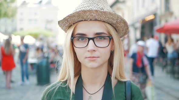 portrait of a happy beautiful blond girl with glasses, a hat and a blue jeans jacket