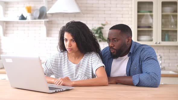 Shocked AfricanAmerican Couple Staring at the Laptop Screen alt