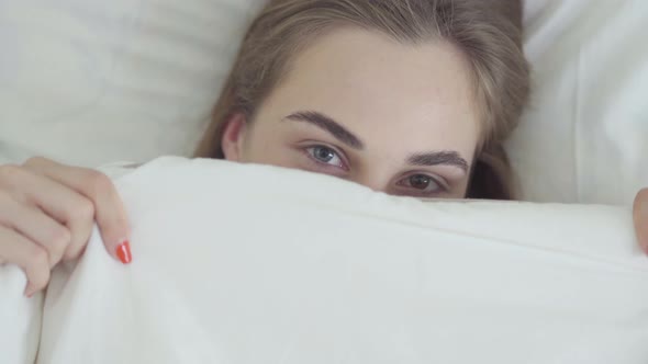 Portrait Cute Young Happy Caucasian Woman with Different Colored Eyes Lying in Bed in the Morning alt