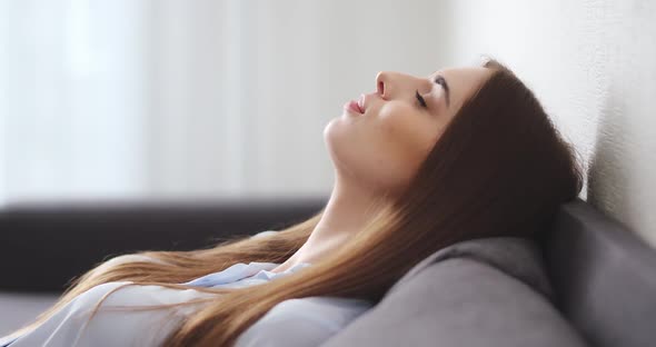 Young Woman Lies Down on the Sofa in the Living Room and Rests Peaceful Female Relaxing After Work alt